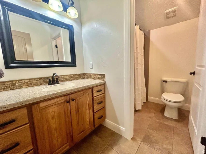 Bathroom vanity featuring a light-toned countertop, a rectangular mirror with a black frame, and wood-finish cabinetry