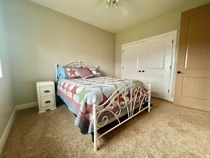 Spacious room featuring neutral carpeting, a ceiling fan with integrated lighting, and a window for natural light