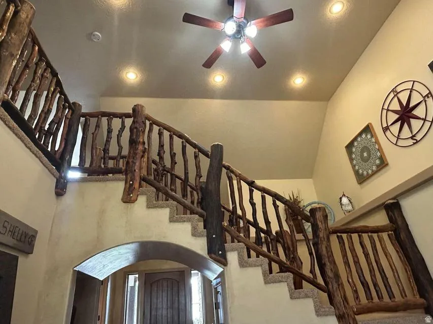 Staircase featuring rustic wood railings, carpeted treads, and an arched entry
