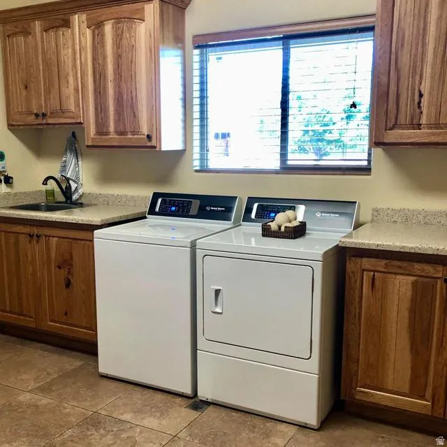 Built-in cabinetry with natural wood finish, stone-finish countertops, ceramic tile flooring, and a single-basin sink with a gooseneck faucet