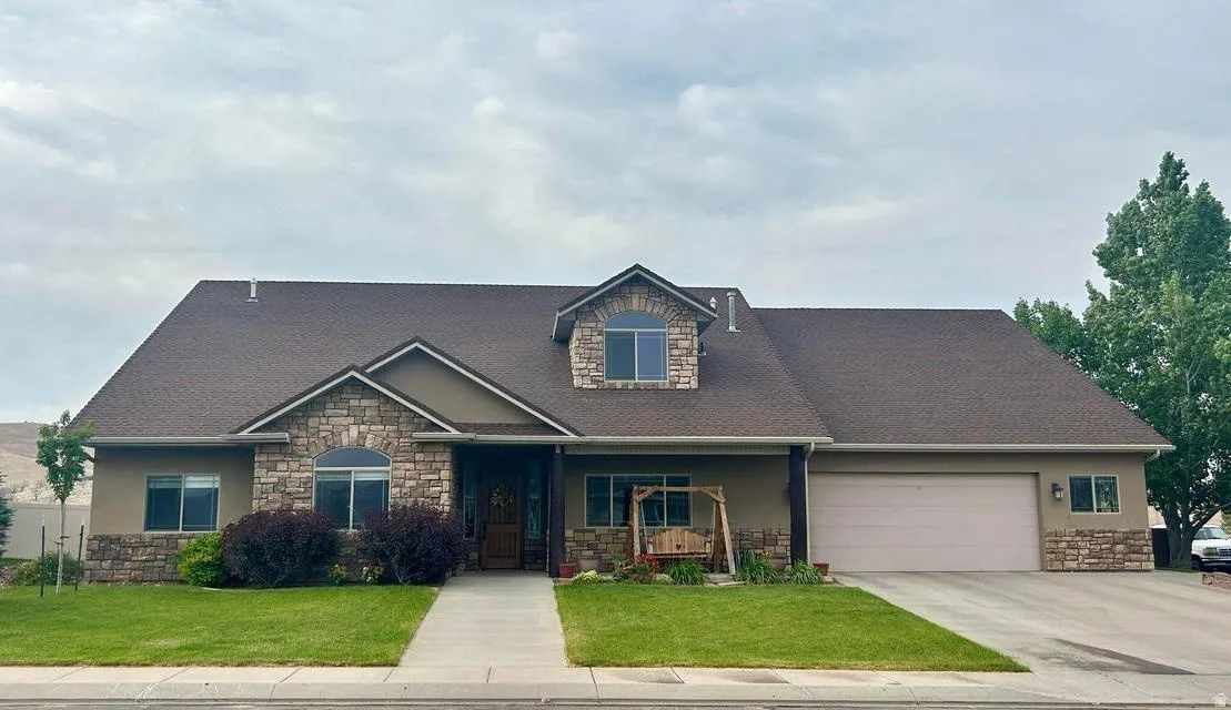 Exterior featuring stone accents, stucco finish, a dormer window, and an attached garage