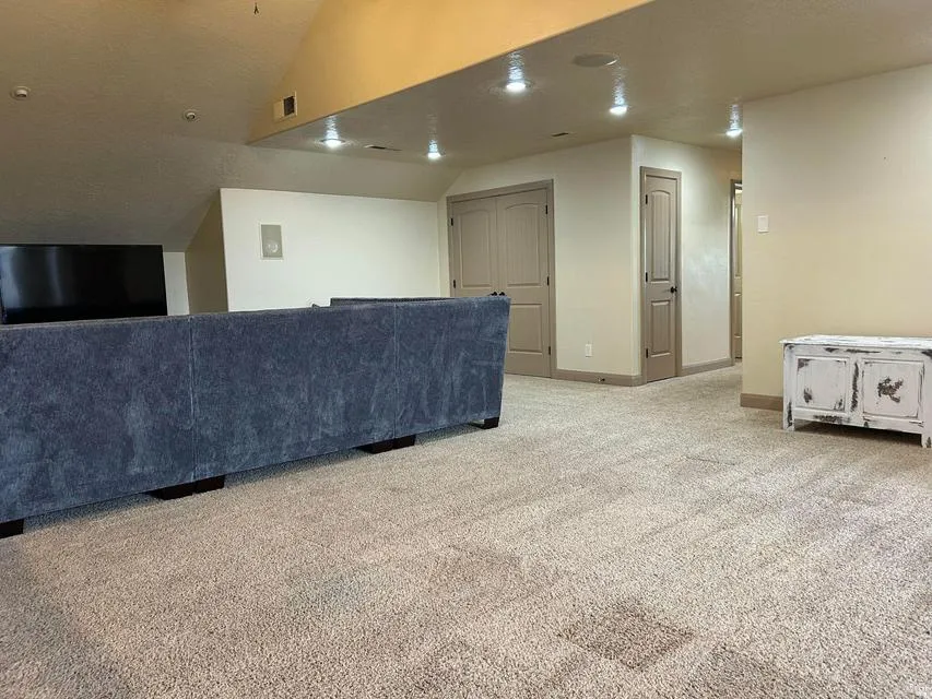Recessed lighting, wall-mounted speakers, sloped ceilings, and neutral-toned walls