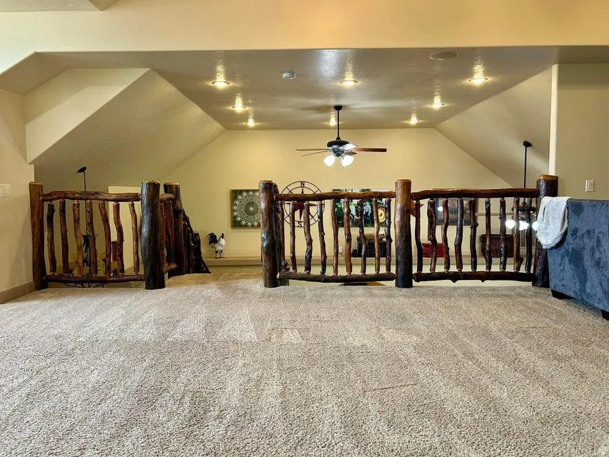 Loft space featuring rustic wood railings, recessed lighting, and a ceiling fan
