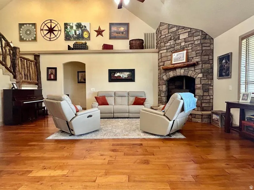 Vaulted ceilings, wood-finish flooring, stone-clad fireplace with wood mantle, and a built-in architectural shelf