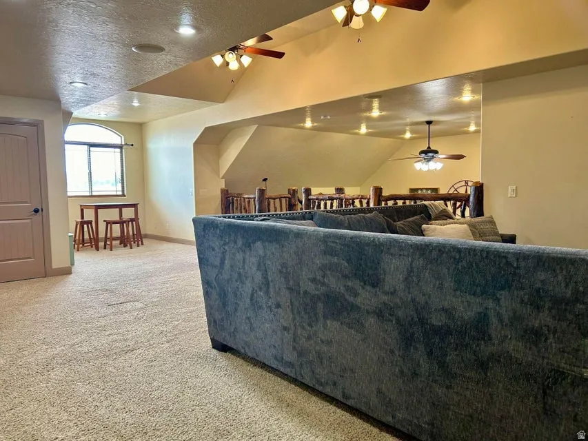 Carpeted open-concept living area with an arched window, recessed lighting, and a paneled door