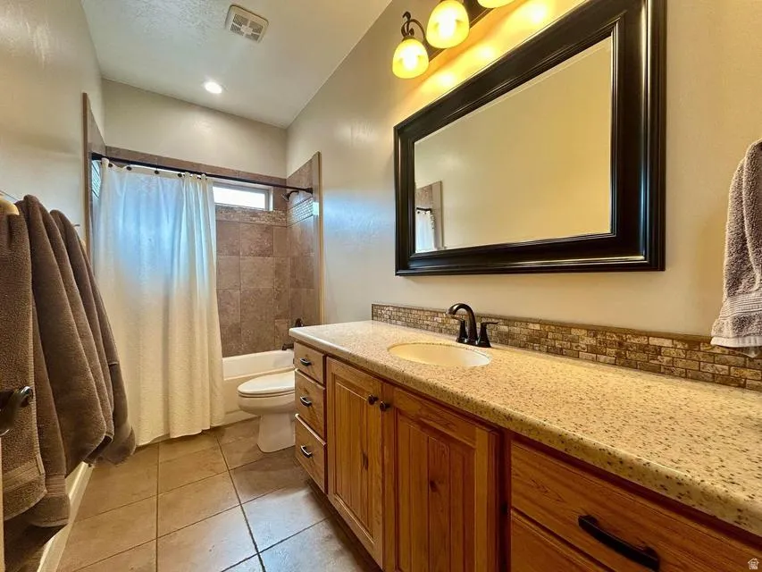 Wood-finish cabinetry with dark hardware and a speckled countertop