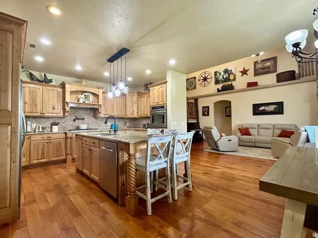 Spacious kitchen featuring wood-finish cabinetry, a large center island with a stone countertop, and stainless steel appliances