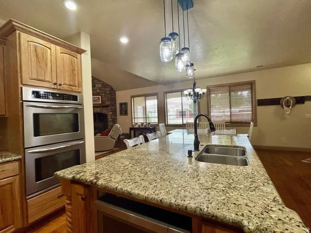 Gourmet kitchen featuring a large island with a double basin sink, granite countertops, and stainless steel double ovens