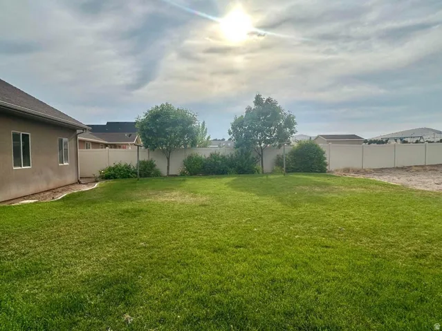 Expansive green lawn with mature trees, bordered by privacy fencing