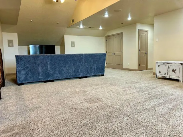 Expansive carpeted area with recessed lighting, integrated wall speakers, and multiple built-in doors