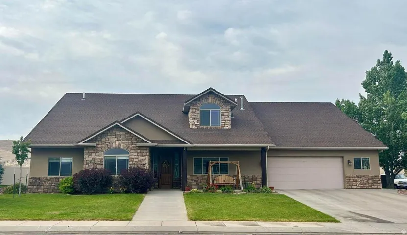 Exterior featuring stone accents, stucco finish, a dormer window, and an attached garage