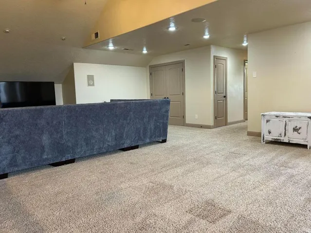 Recessed lighting, wall-mounted speakers, sloped ceilings, and neutral-toned walls