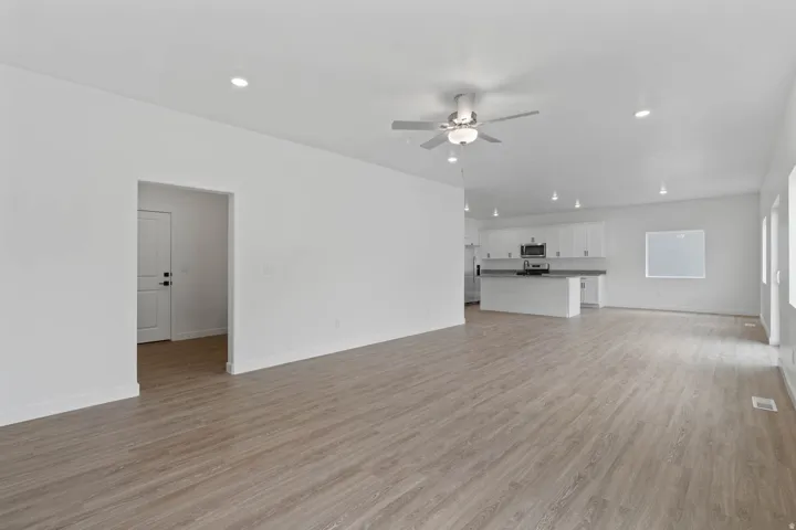 Open-concept living space with wood-finish flooring, recessed lighting, and a ceiling fan