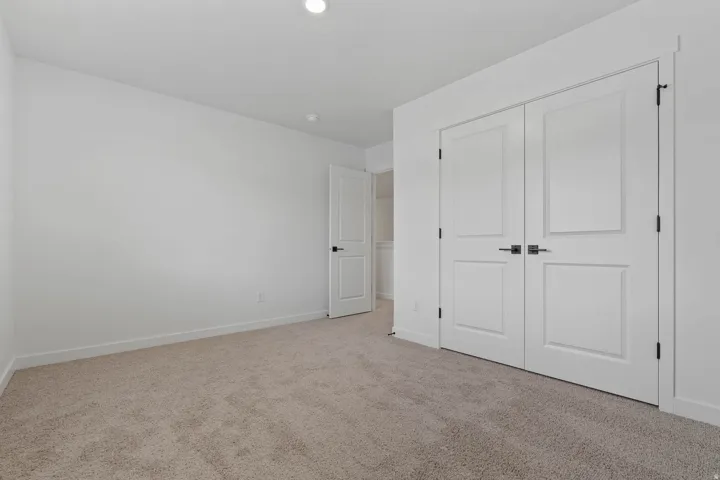 Recessed ceiling lighting, white walls, light tan carpeting, and white doors with matte black hardware