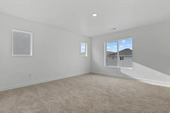Neutral-toned carpeting, white walls, recessed ceiling lighting, and multiple windows