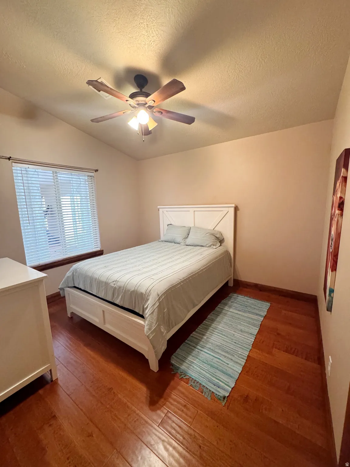 Vaulted ceiling, wood-finish flooring, ceiling fan with integrated lighting, window with blinds