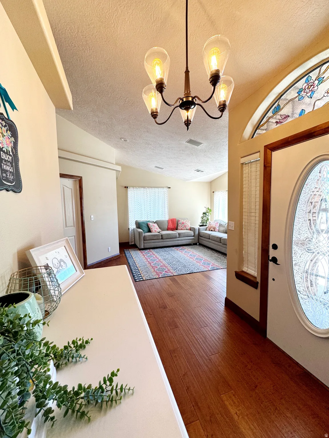 Foyer featuring wood-finish flooring, a decorative chandelier, and an arched transom window with stained glass detailing