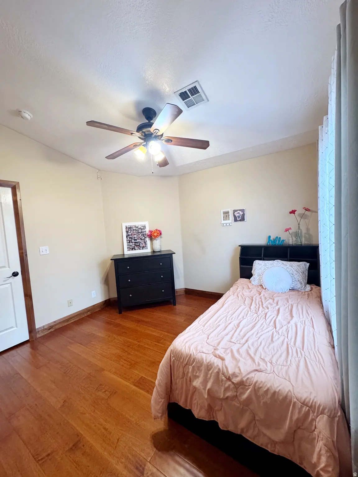 Wood-finish flooring, ceiling fan with integrated lighting, and a white interior door with dark hardware