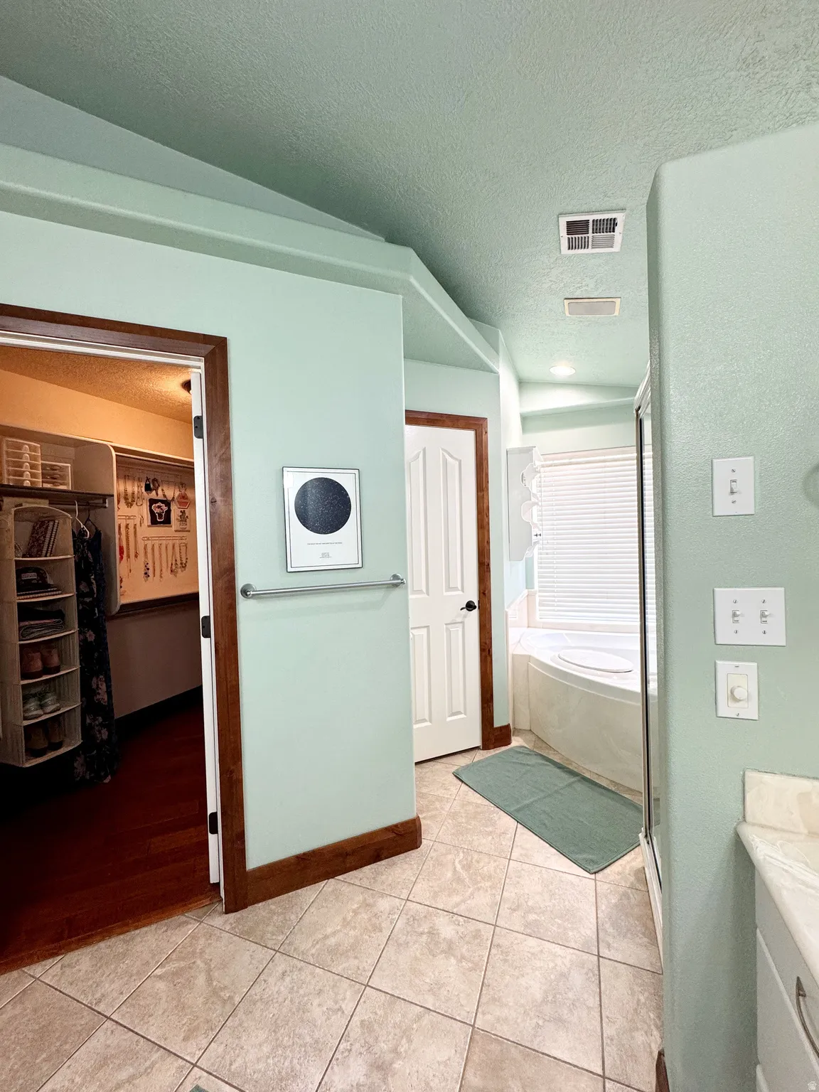 Tiled flooring with a built-in corner bathtub, an adjacent shower enclosure, and wood-trimmed doorways