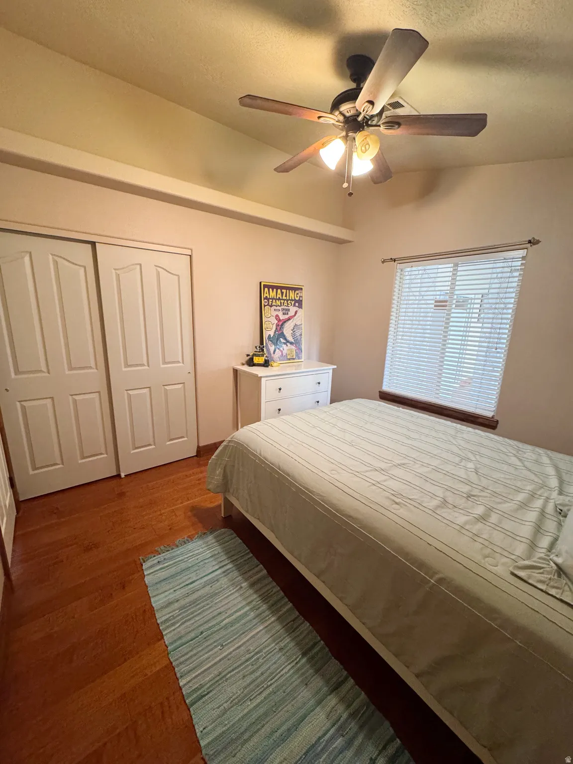 Vaulted ceiling with a ceiling fan, wood-finish flooring, and sliding closet doors