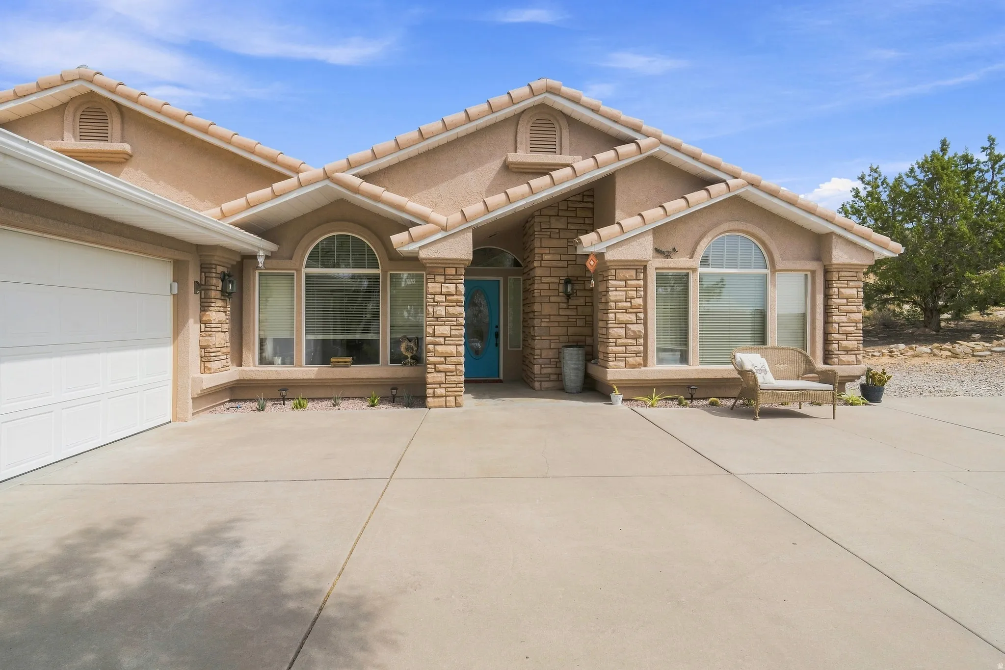 Stucco exterior with stone accents, arched windows, tile roof, and an attached garage