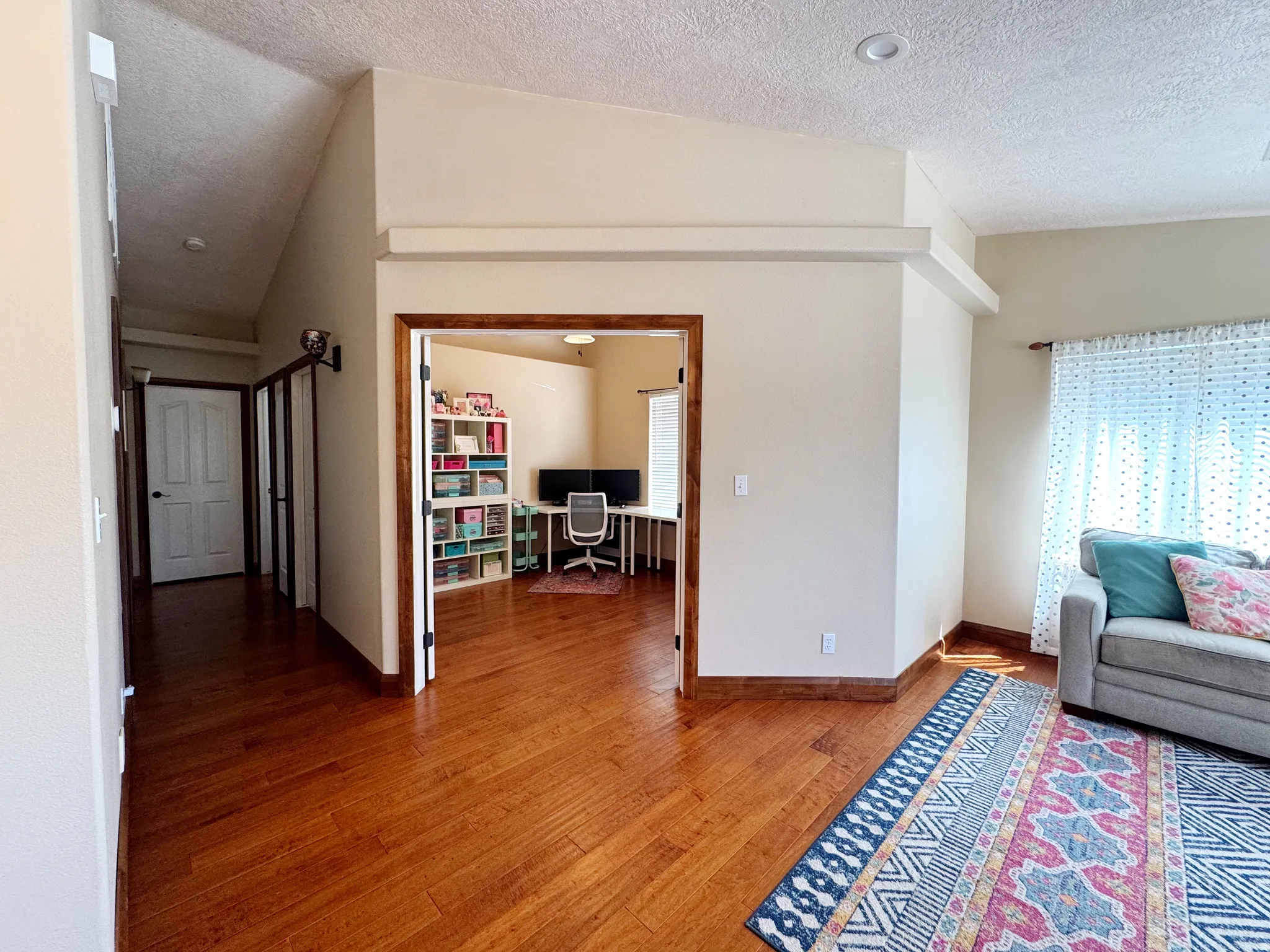 Wood-finish flooring throughout, vaulted ceiling, recessed lighting, and a distinct room for a dedicated workspace