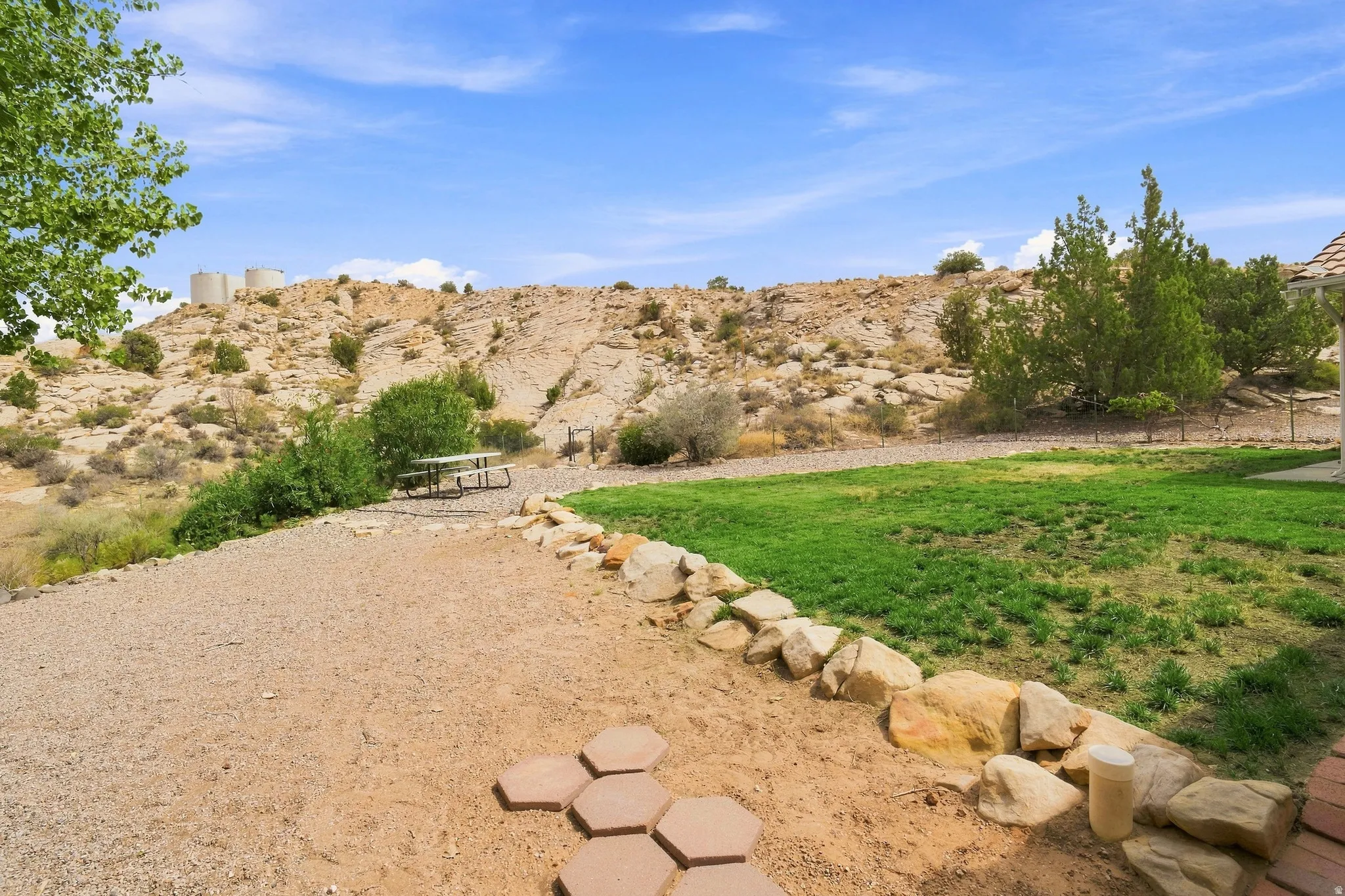 Expansive outdoor space featuring a gravel patio, rock landscaping, and a manicured lawn