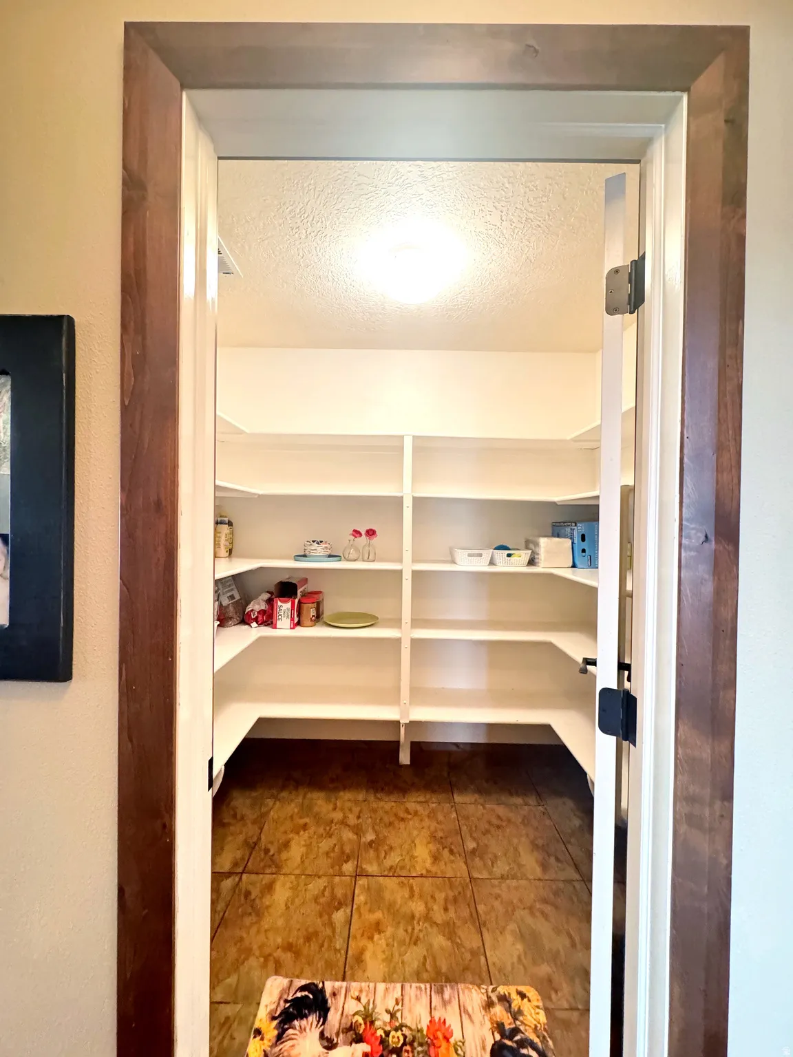 Walk-in pantry featuring extensive built-in shelving, tile flooring, and integrated ceiling lighting