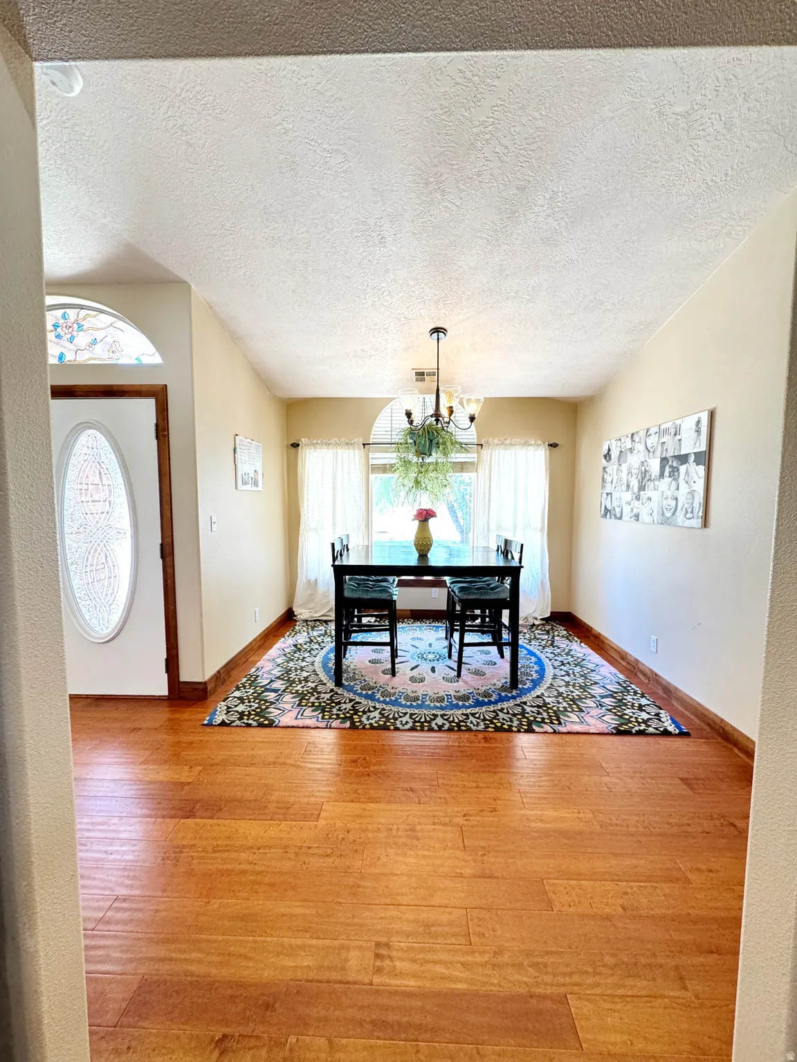 Wood-finish flooring throughout, a decorative glass entry door with an arched transom, and a chandelier lighting fixture