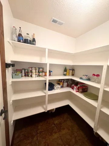 Extensive pantry featuring multiple tiers of built-in shelving, corner storage, and durable tile flooring