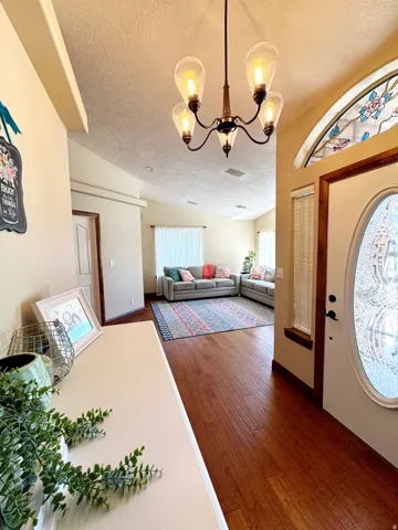 Foyer featuring wood-finish flooring, a decorative chandelier, and an arched transom window with stained glass detailing