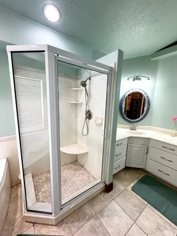 Glass-enclosed shower with a built-in bench, two corner shelves, and a tiled floor
