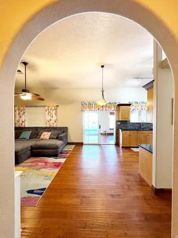Archway entryway opening to a spacious interior with wood-finish flooring