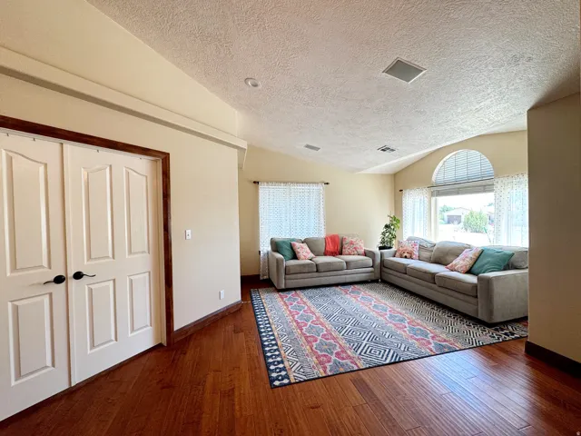 Vaulted ceiling with an arched window, wood-finish flooring, and recessed lighting