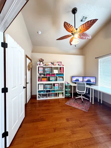 Wood-finish flooring throughout, vaulted ceiling, and a ceiling fan with integrated lighting