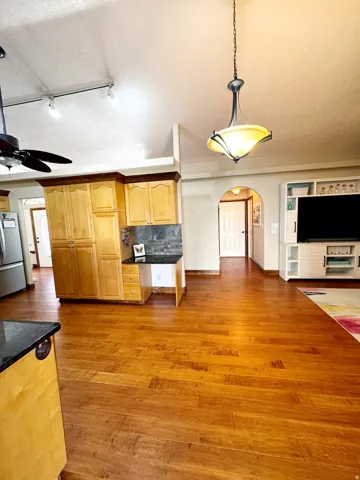 Hardwood flooring throughout, vaulted ceiling, built-in cabinetry, recessed lighting, and an arched doorway