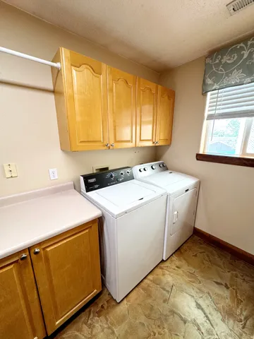 Laundry area featuring upper and lower cabinetry, a light-toned countertop, and patterned flooring