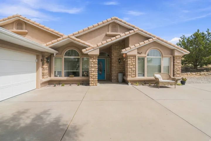 Stucco exterior with stone accents, arched windows, tile roof, and an attached garage