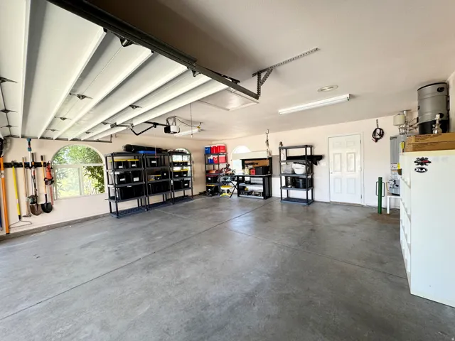 Spacious garage with concrete flooring, arched windows, and white garage door panels