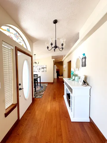 Wood-finish flooring, recessed ceiling, chandelier lighting, arched stained-glass transom window, and white oval-lite entry door