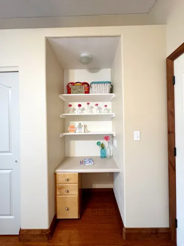 Built-in desk with three drawers, three floating shelves, and an overhead light fixture