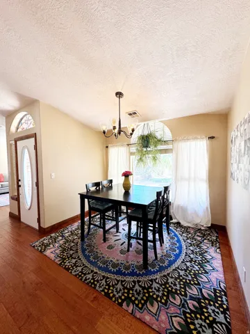 Hardwood-finish flooring, overhead chandelier, arched transom window, and a window with blinds
