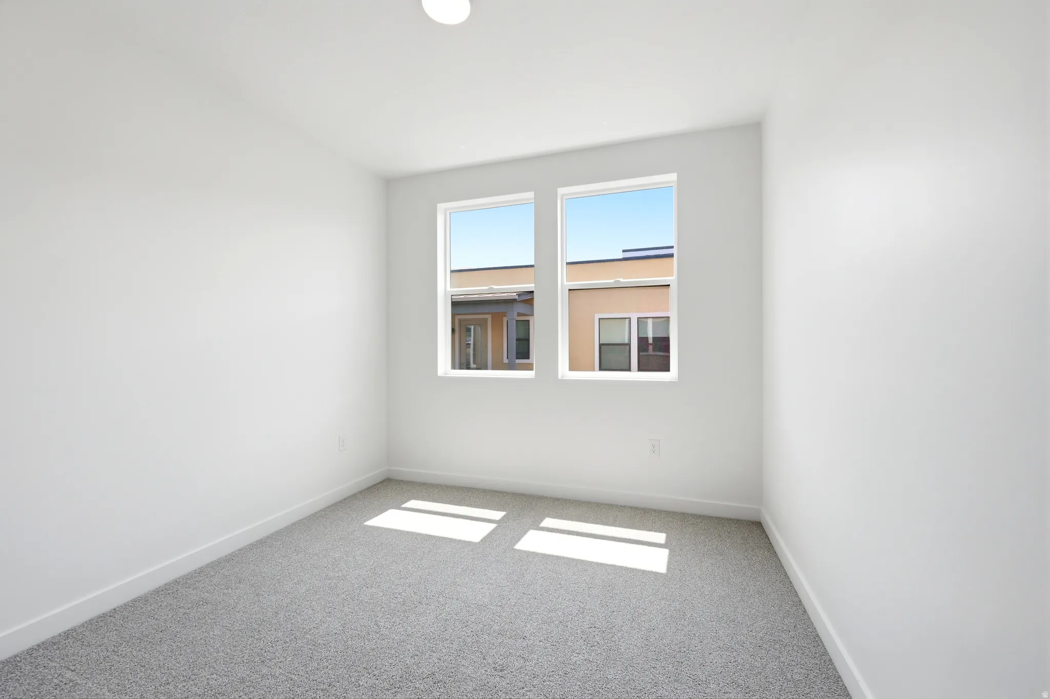 Bright room with light gray carpet, white walls, and a recessed ceiling light