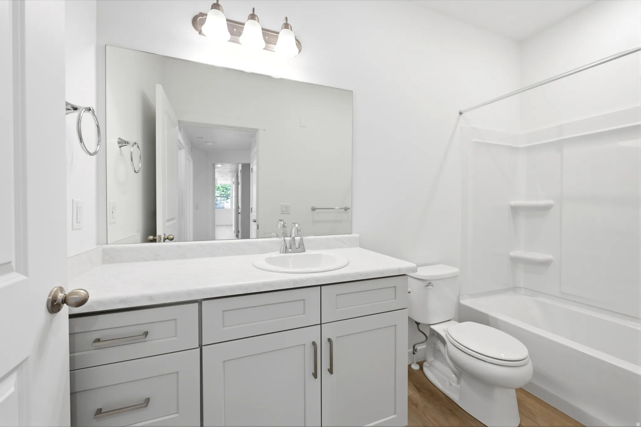 White bathroom featuring a vanity with a white countertop, undermount sink, and light gray cabinetry with brushed nickel hardware