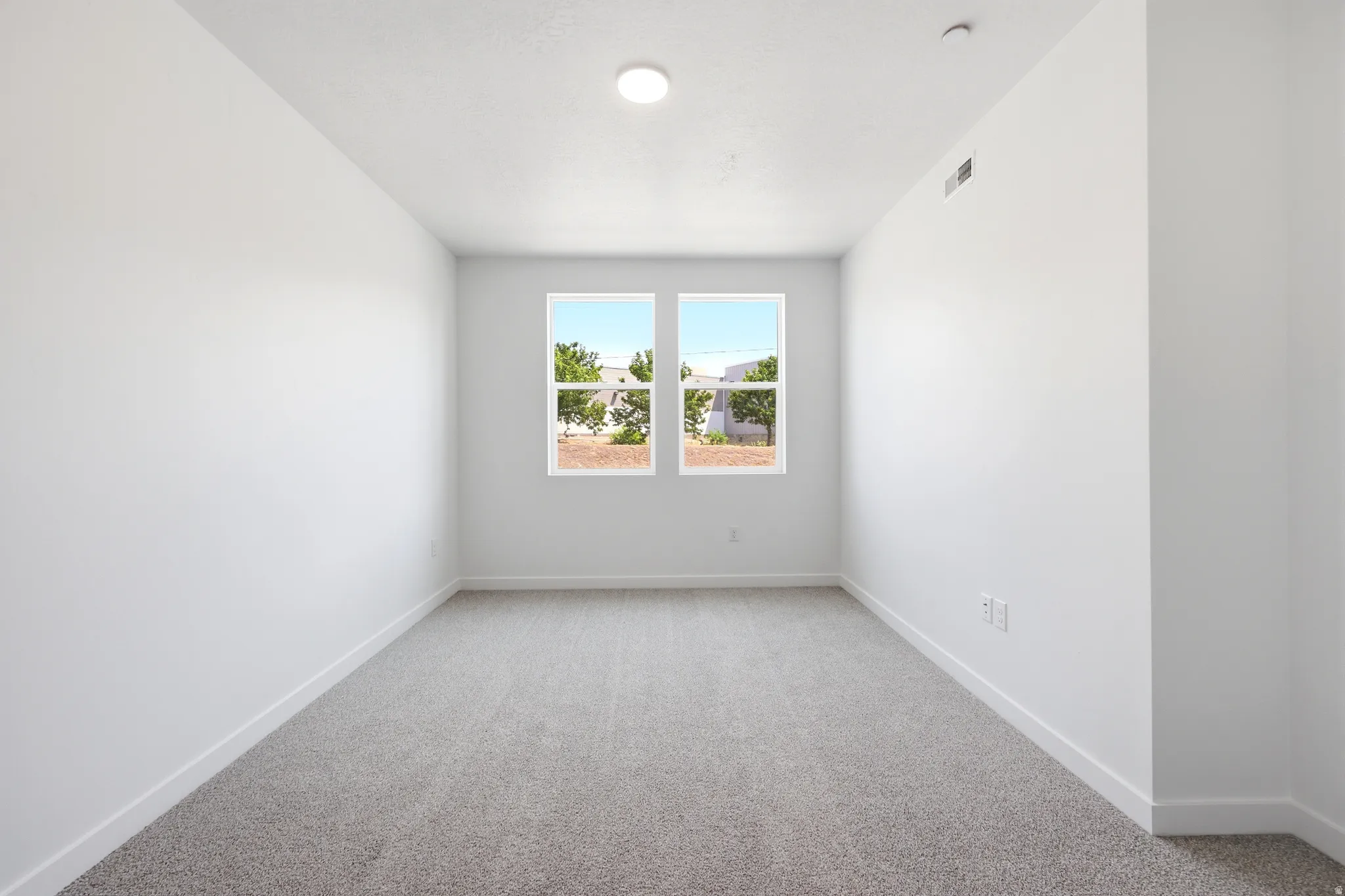 White walls, gray carpet, and a pair of windows