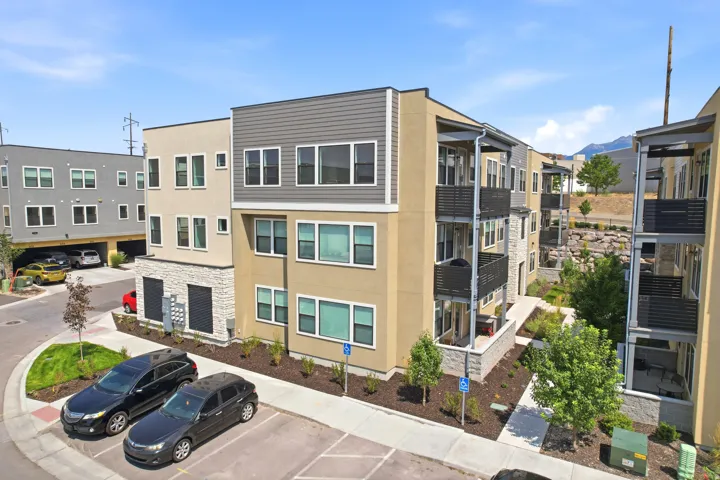 Multi-story building featuring contemporary architecture, multiple balconies, a mix of stucco and stone-finish siding, and integrated landscaping