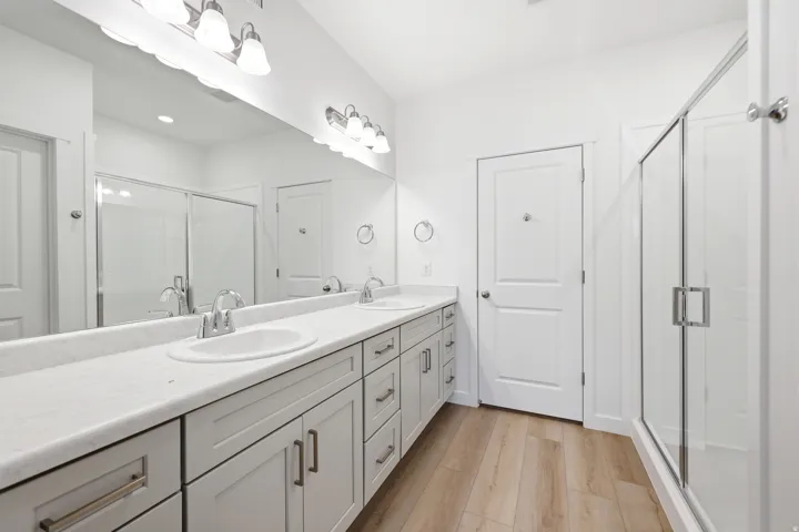 Dual sink vanity with light gray cabinetry, white countertops, and chrome fixtures