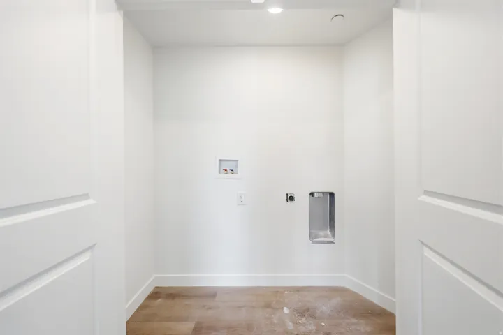 Dedicated utility area featuring wood-finish flooring and bright white walls