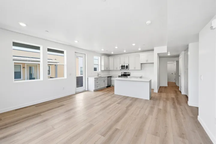 Open-concept living area with wood-finish flooring, recessed lighting, and multiple windows