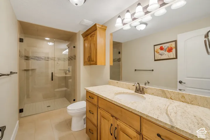 Enclosed shower with glass paneling and patterned tile accent, wood-finish vanity with countertop, undermount sink, and wall-mounted mirror